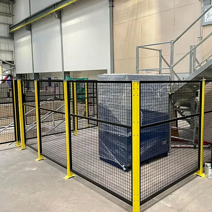 Black mesh guarding with yellow posts in an industrial building.